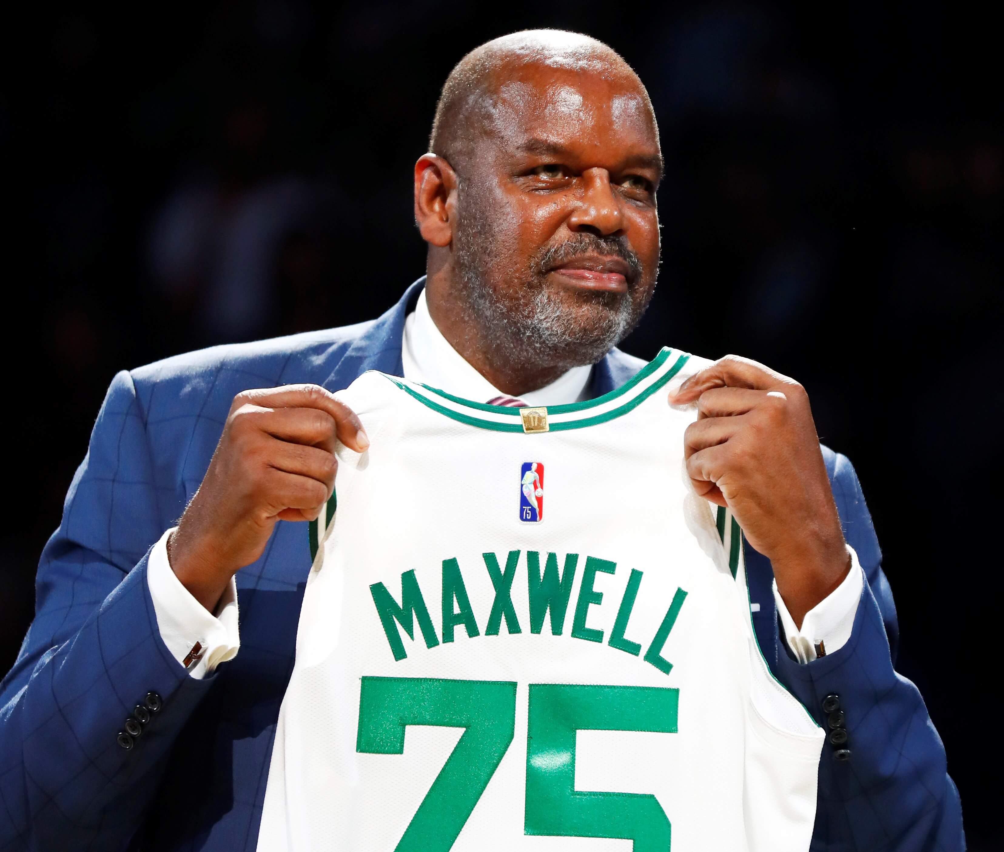 Former Boston Celtics player Cedric Maxwell holds up a jersey.