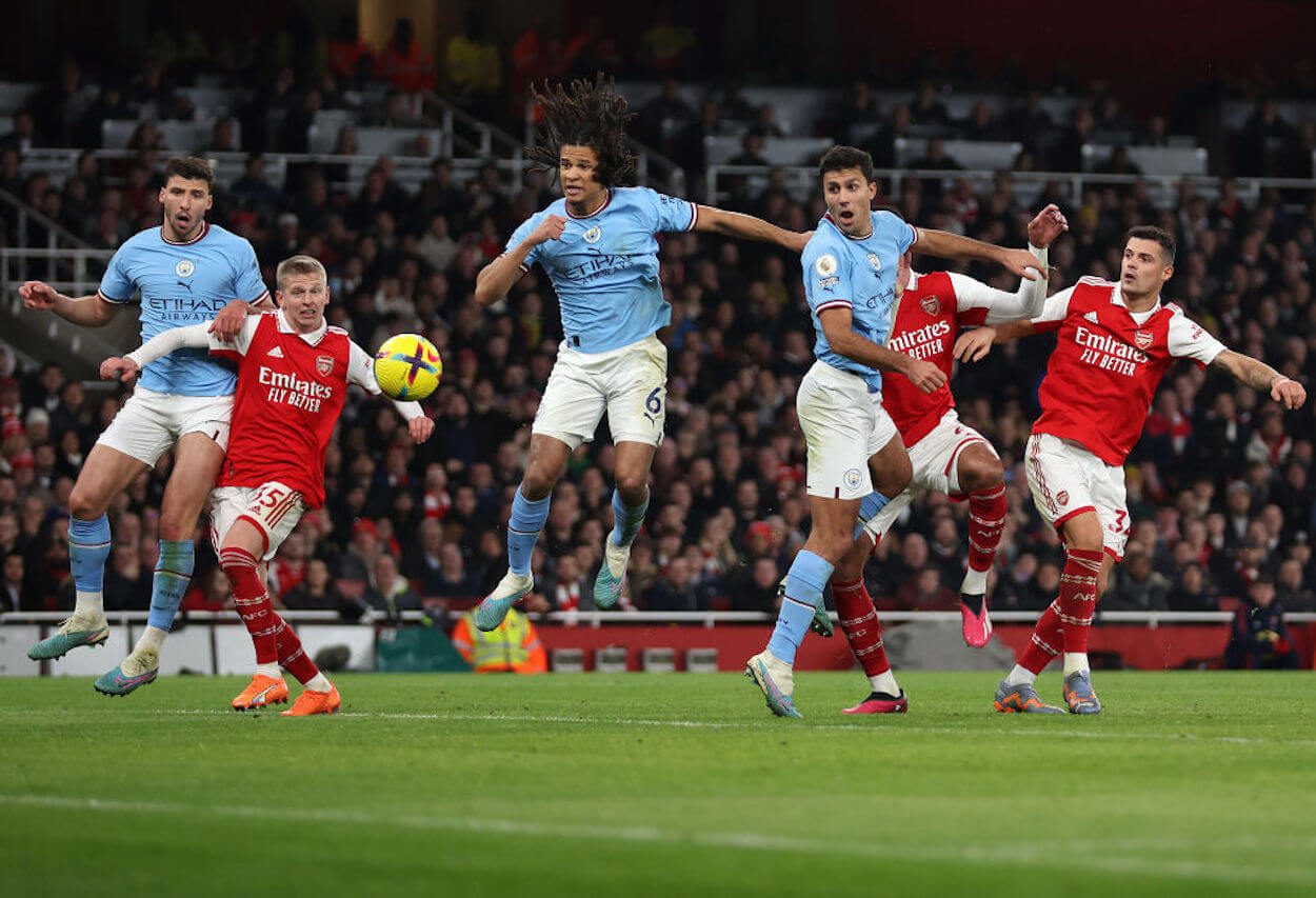 Arsenal and Manchester City players battle for a ball in the box.