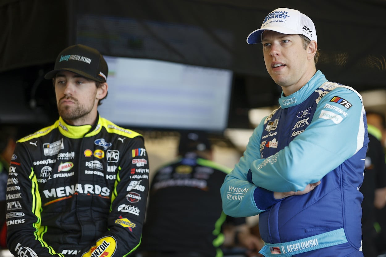 Brad Keselowski and Ryan Blaney stand in garage.