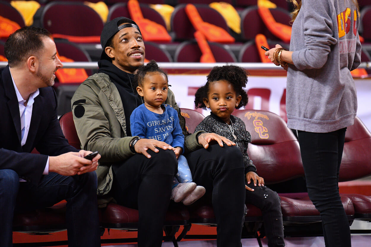 DeMar DeRozan and his daughters watch a college basketball game.
