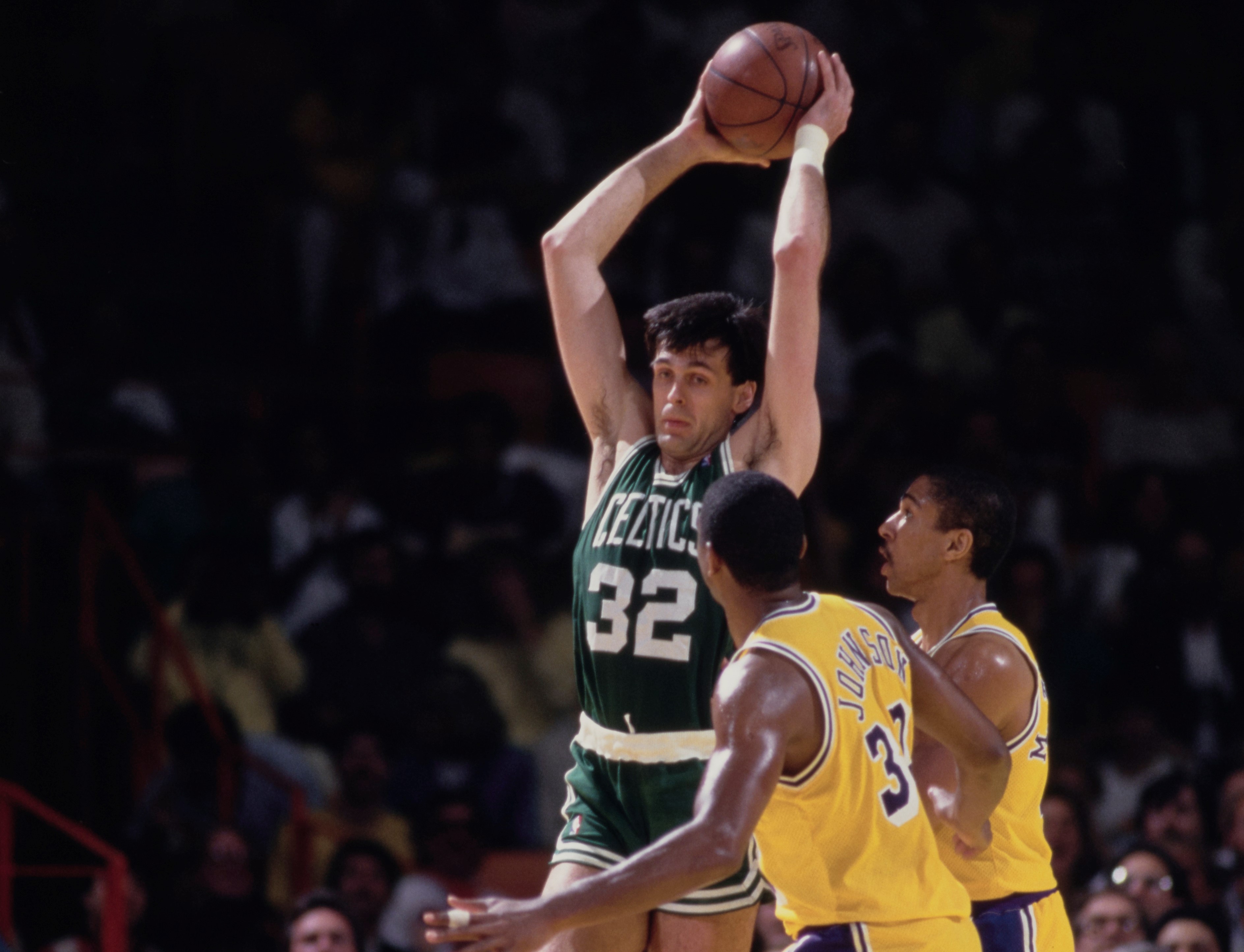 Kevin McHale of the Boston Celtics pulls down a rebound over Magic Johnson and Mychal Thompson of the Los Angeles Lakers.
