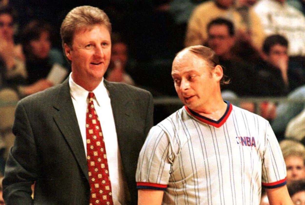 Larry Bird (L) talks with a referee.