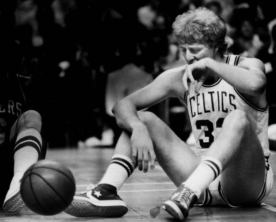 Larry Bird sits on the floor after diving for a loose ball.