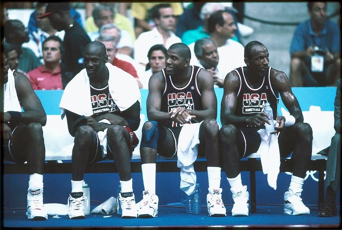 Dream Team members, Michael Jordan, Magic Johnson, and Clyde Drexler, sit on the bench during a game