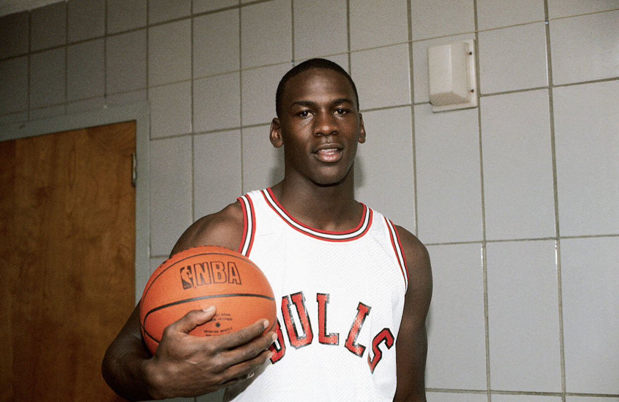 A young Michael Jordan poses for a picture holding a basketball.