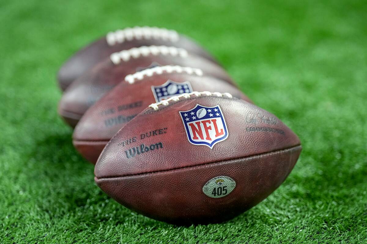 Four Wilson brand footballs sporting the NFL logo rest on the field before a 2022 game