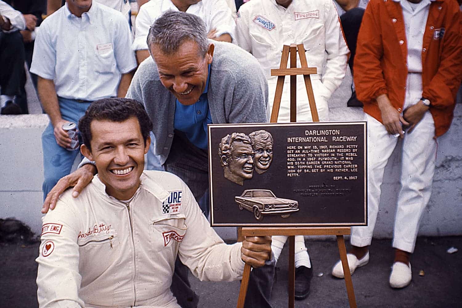 Richard and Lee Petty pose with a plaque presented by Darlington Raceway. It commemorated the younger Petty's 55th career NASCAR Cup win in the Rebel 400 held at Darlington. That victory allowed him to surpass his dad's win total and made them No. 1 and 2 in career NASCAR Cup victories. | ISC Images & Archives via Getty Images