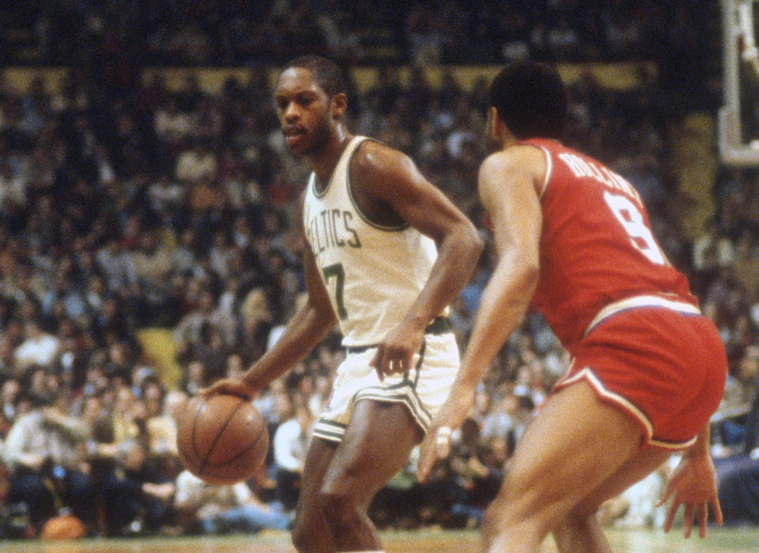 Nate Archibald of the Boston Celtics dribbles the ball while guarded by Lionel Hollins of the Philadelphia 76ers.