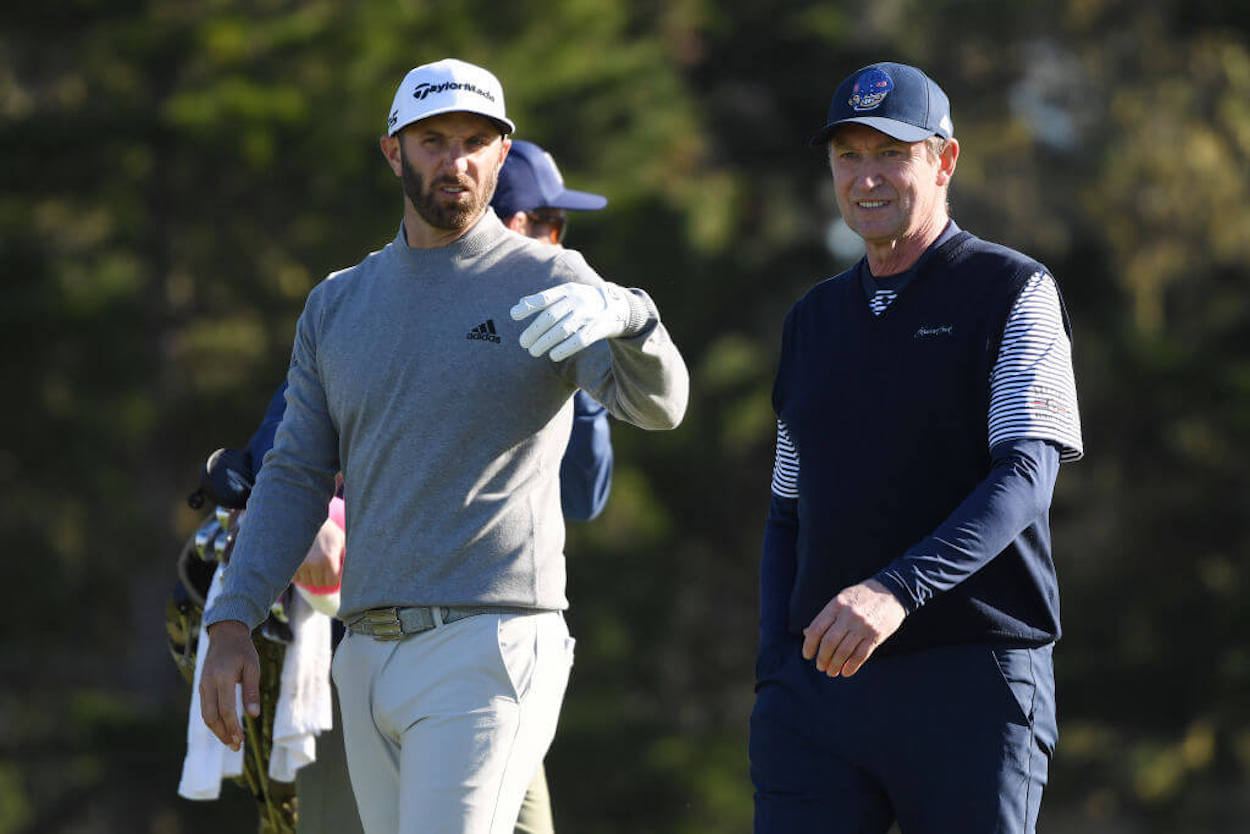 Dustin Johnson (L) and Wayne Gretzky walk together on the golf course.