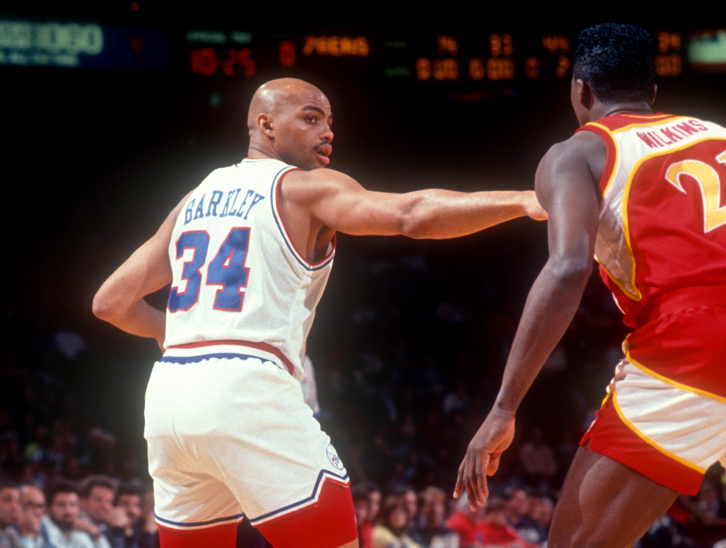 Charles Barkley of the Philadelphia 76ers looks to pass as Dominique Wilkins of the Atlanta Hawks defends.