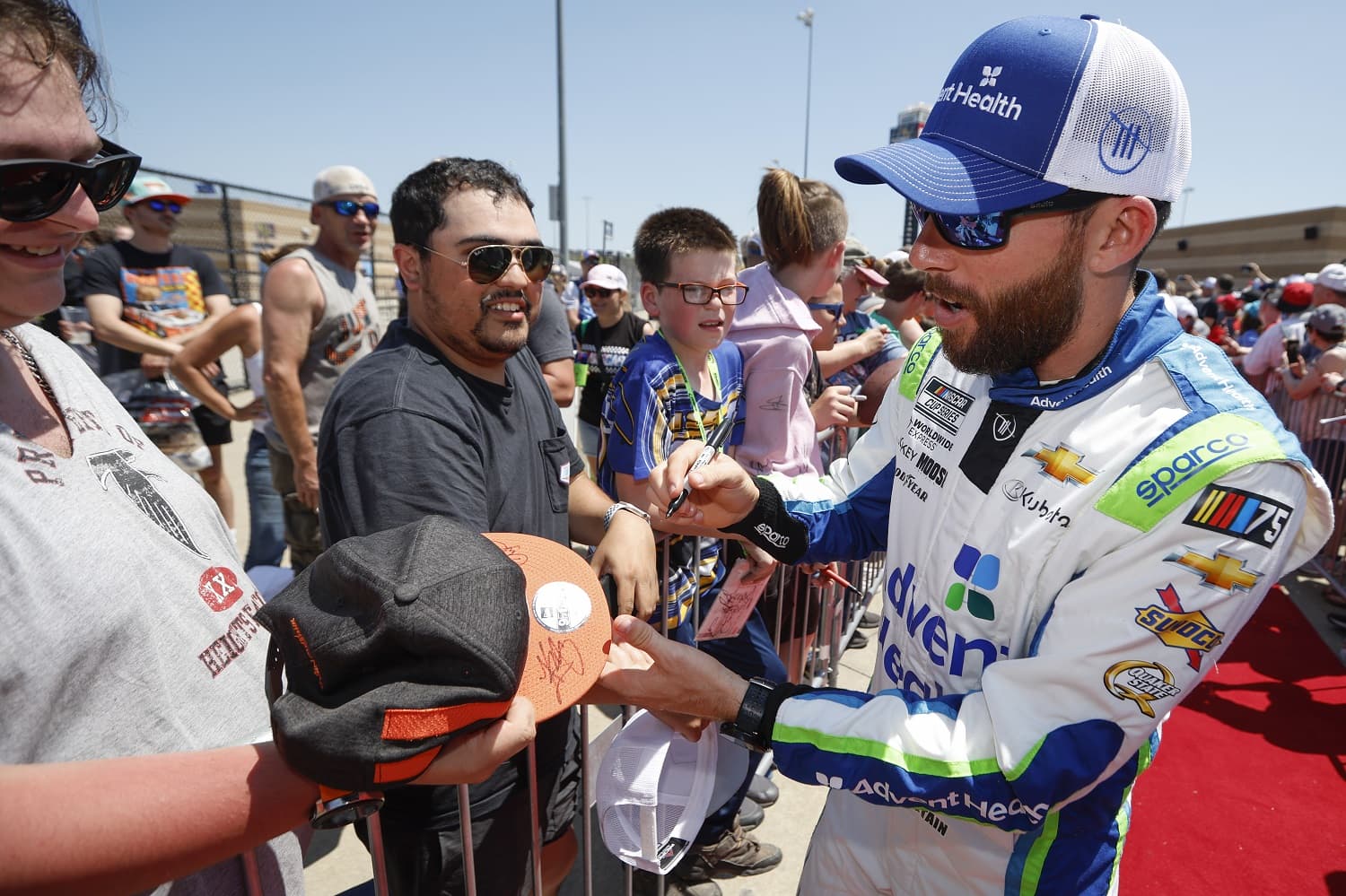 Ross Chastain signs autographs on the red carpet prior to the NASCAR Cup Series Advent Health 400 at Kansas Speedway on May 7, 2023.