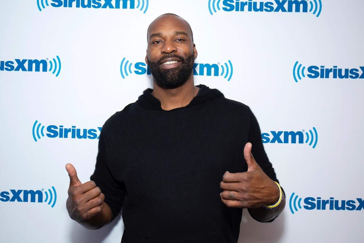 NBA player Baron Davis gives a thumbs up to cameras at a media event while wearing a black sweater