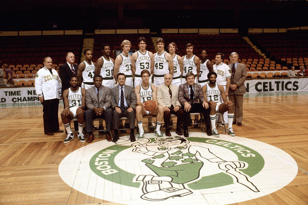 Cedric Maxwell (front row, left) and Red Auerbach (front row, center) pose as part of a Boston Celtics team photo.