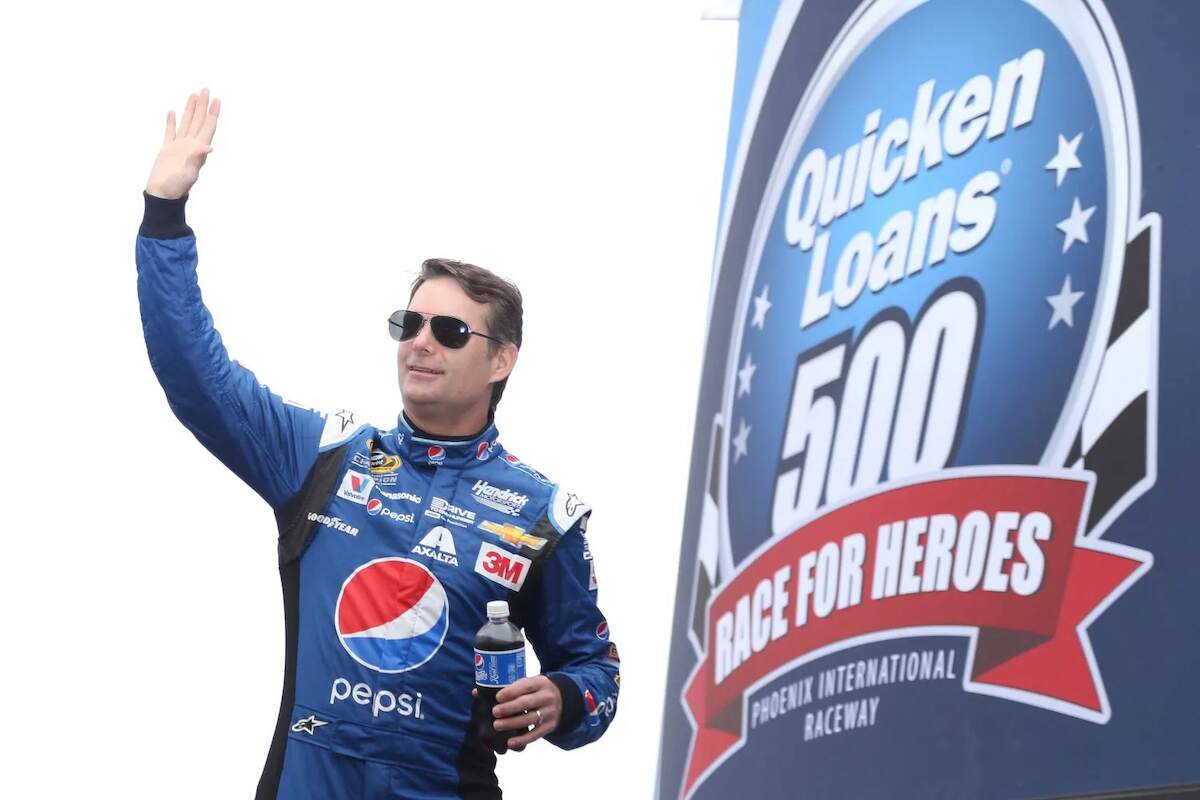 Jeff Gordon waves at fans while holding a Pepsi