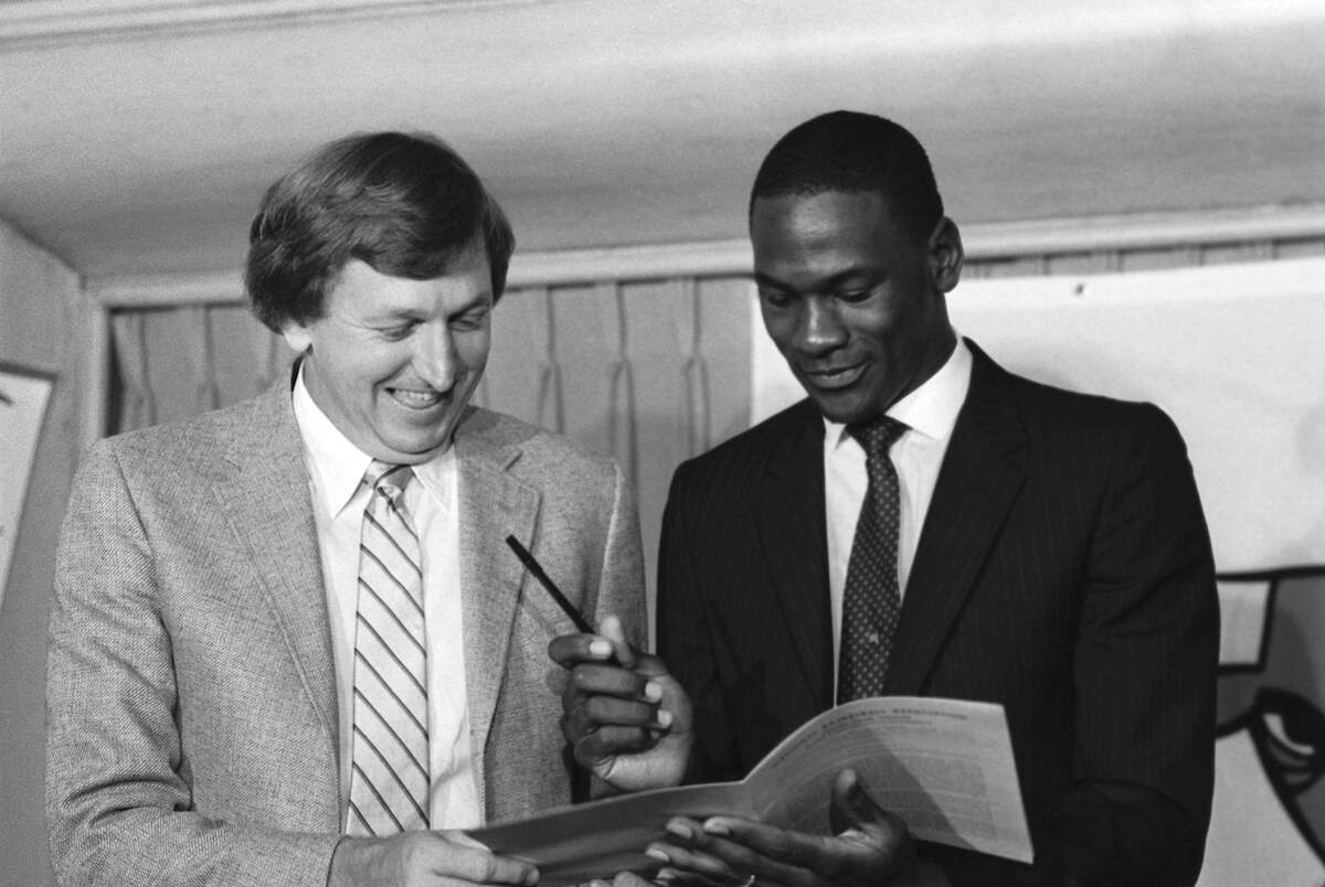 Basketball star Michael Jordan looks over the multi-million dollar contract he signed with the Chicago Bulls as Bulls general manager Rod Thorn looks on