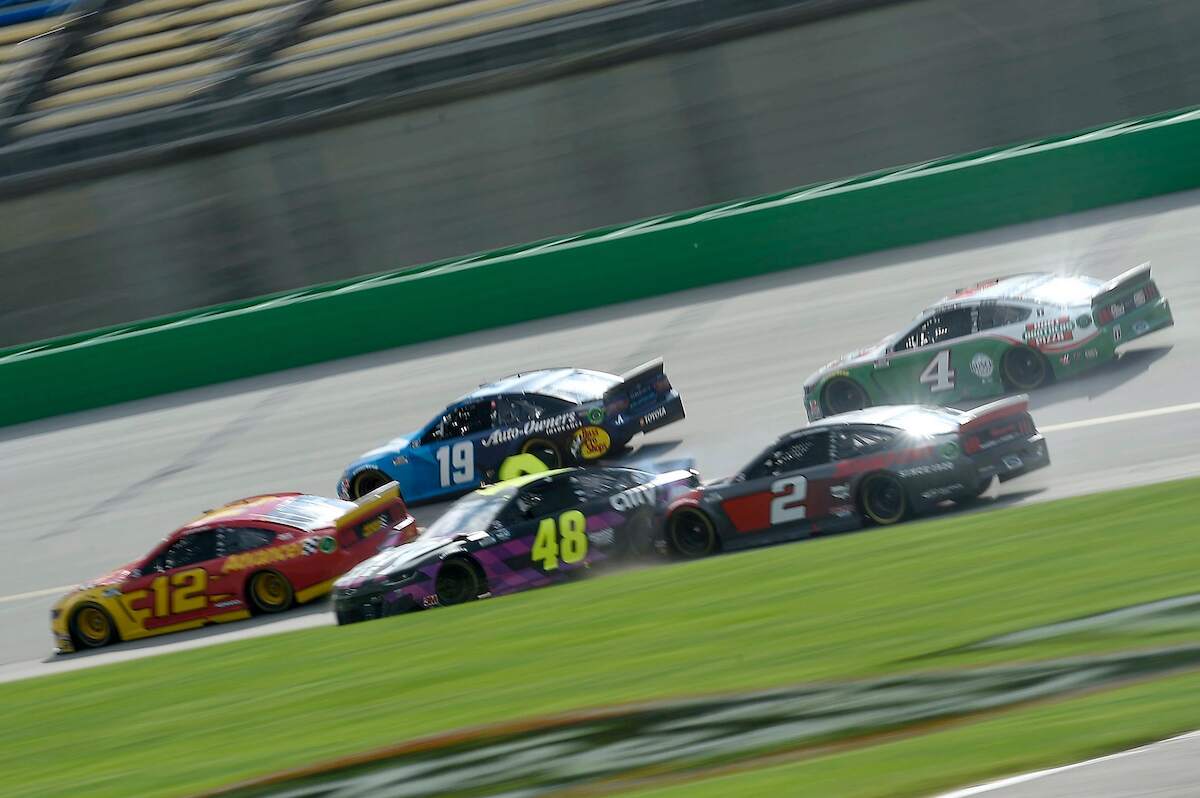 Five NASCAR vehicles speed along the racetrack