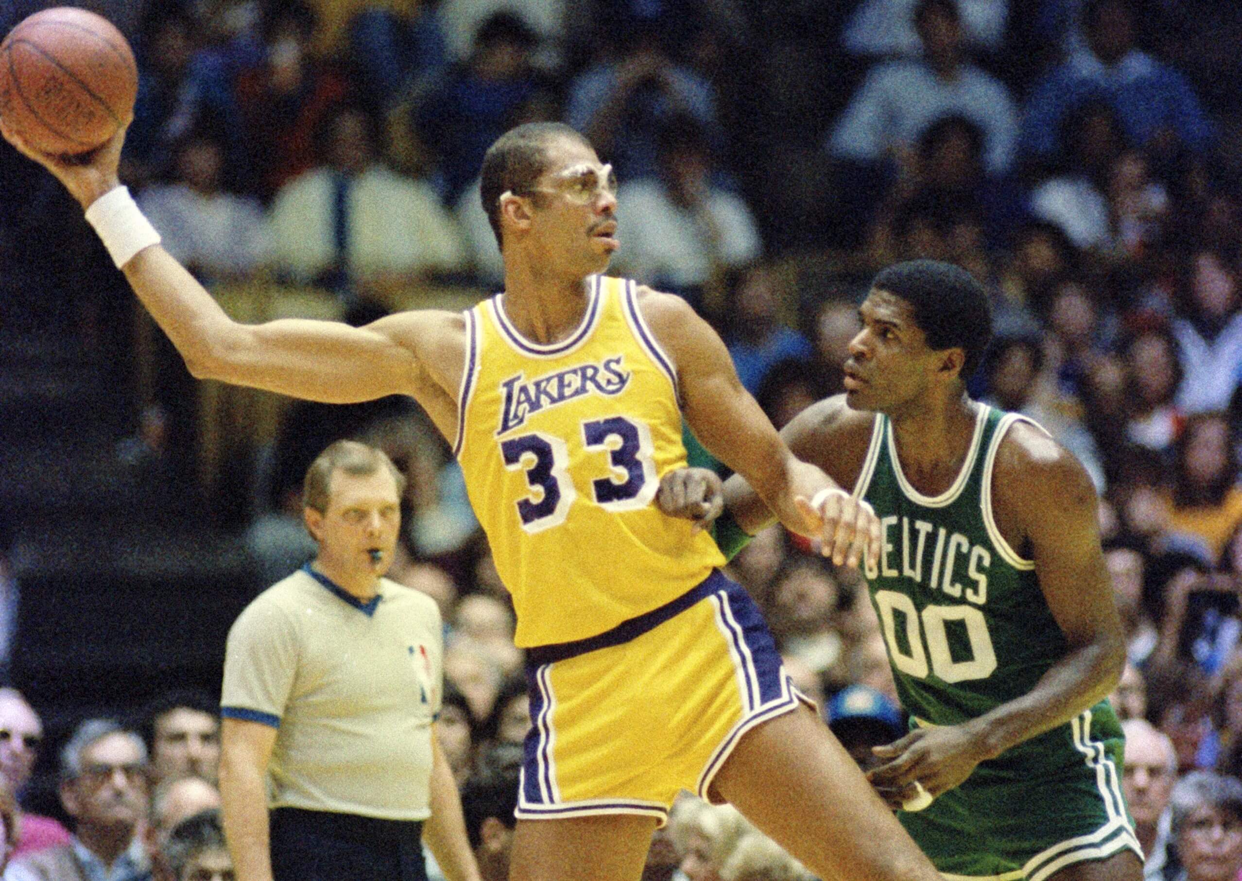 Los Angeles Lakers center Kareem Abdul-Jabbar readies to pass the ball as Robert Parish defends.