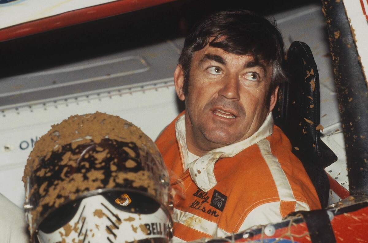 Driver Bobby Allison takes of his mud-covered helmet