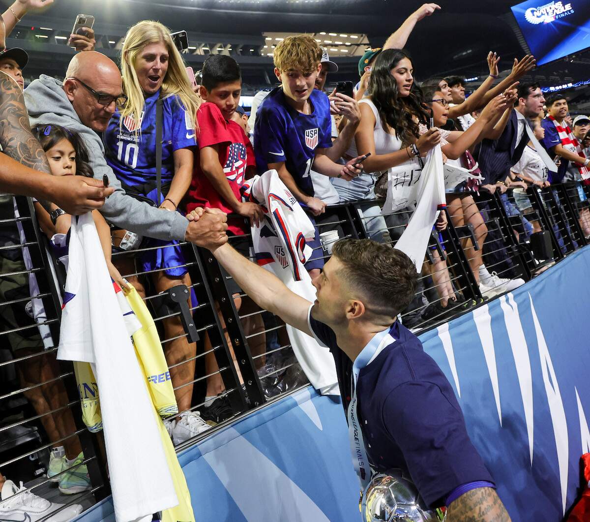 Soccer player Christian Pulisic of the United States reaches out to his father Mark Pulisic and mother Kelley Pulisic while holding the best player award after the team's 2-0 victory over Canada in the 2023 CONCACAF Nations League Final