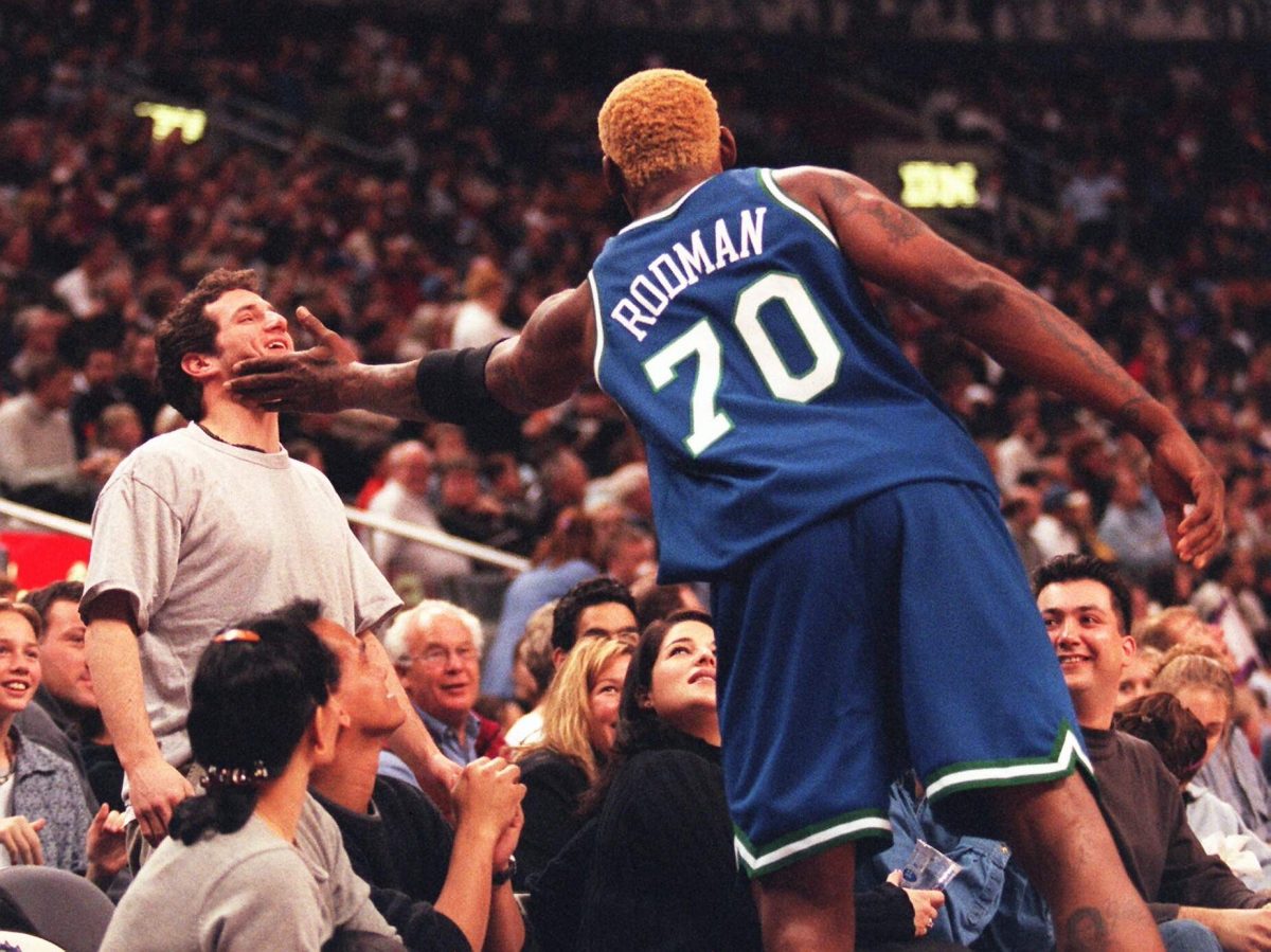 Mavericks player Dennis Rodman reaches out to owner Mark Cuban during an NBA game