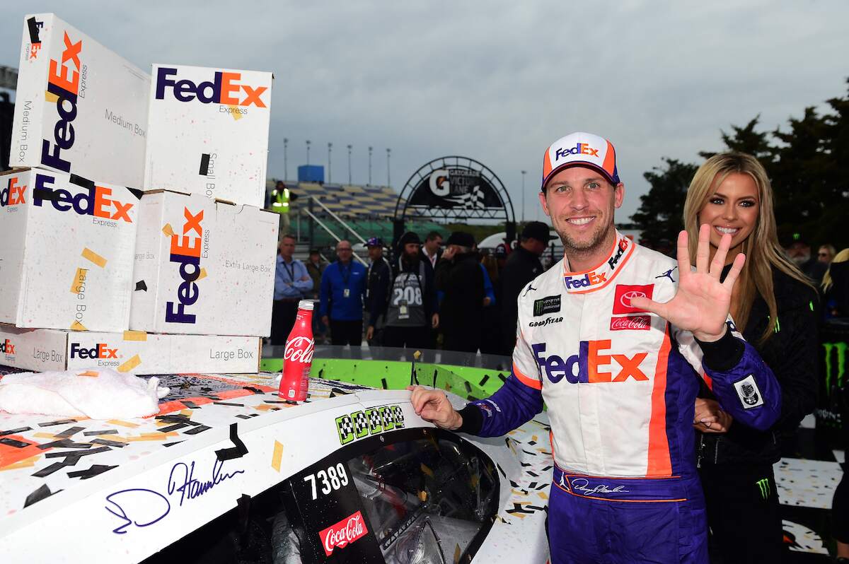 Denny Hamlin, driver of the #11 FedEx Office Toyota, poses with the winner's decal on his car in Victory Lane after winning the Monster Energy NASCAR Cup Series Hollywood Casino 400 at Kansas Speedway in 2019