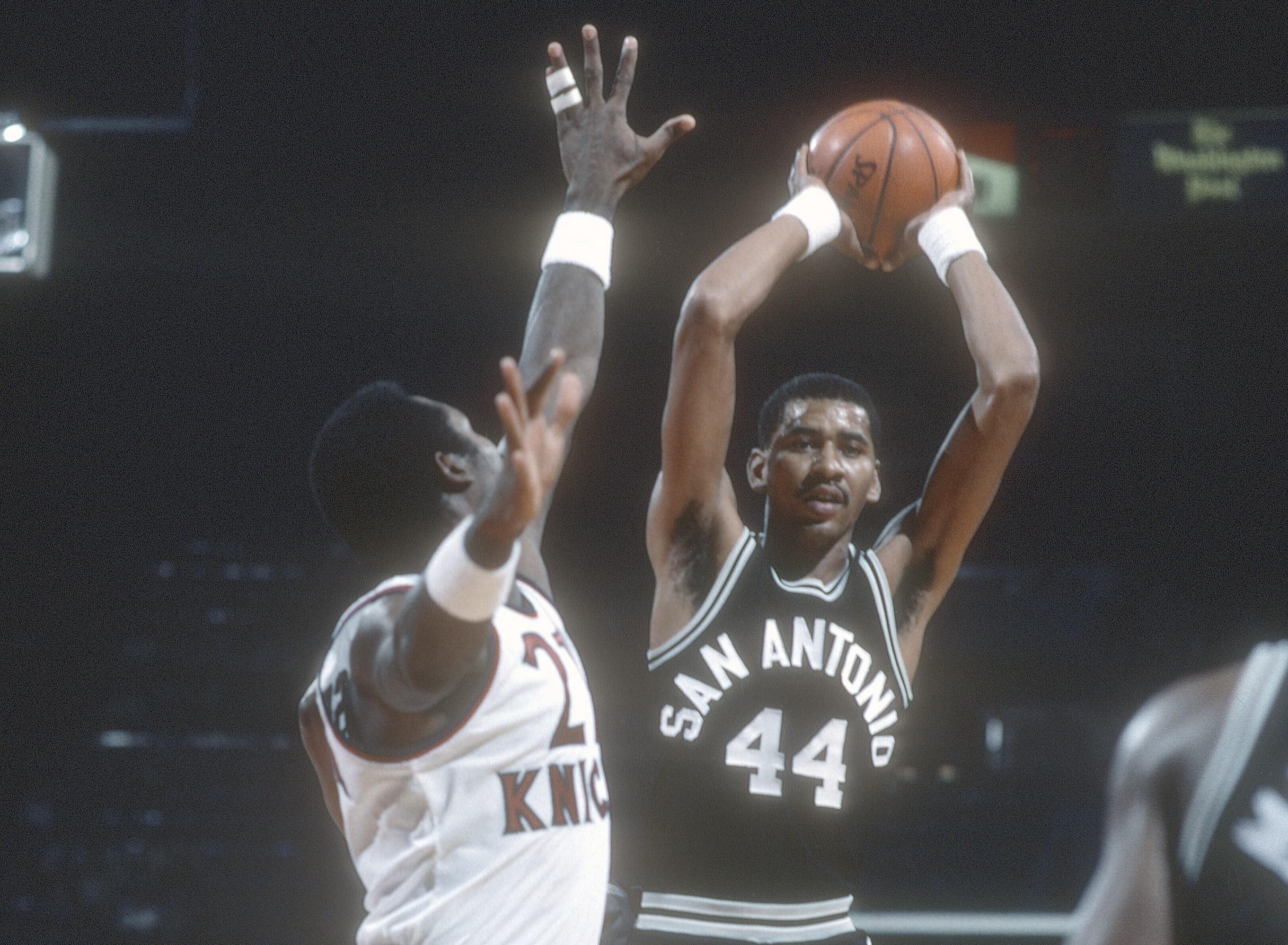 George Gervin of the San Antonio Spurs looks to pass over the top of Campy Russell of the New York Knicks.