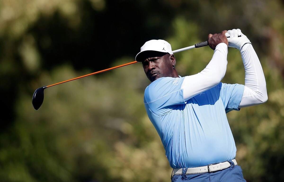 Michael Jordan playing golf in a blue polo and white hat