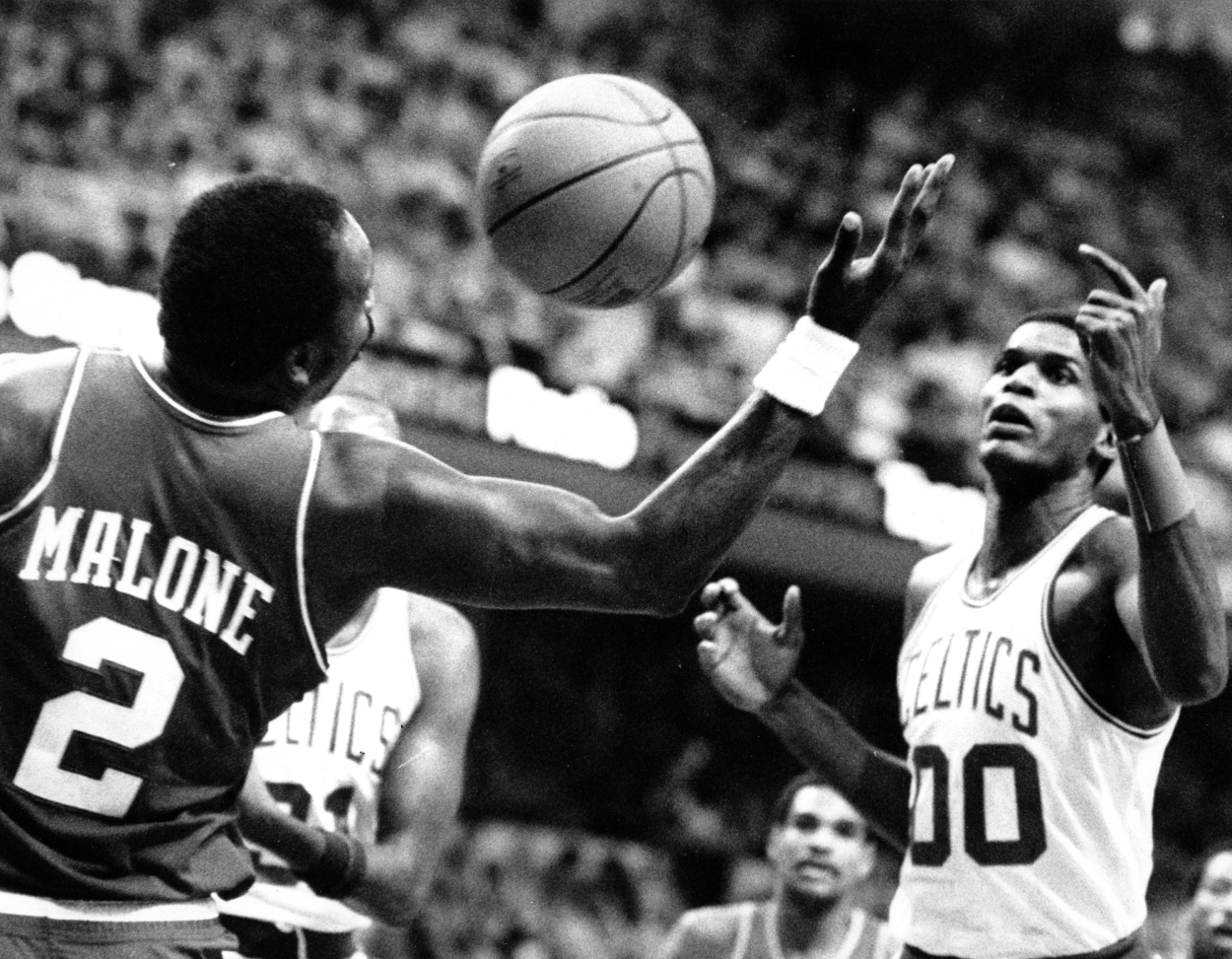 Philadelphia 76ers center Moses Malone, left, and the Boston Celtics center Robert Parish reach for the ball.