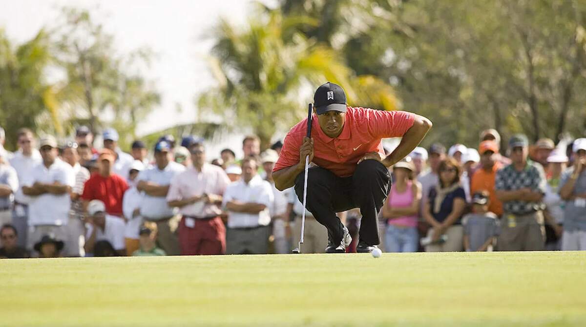 Golf legend Tiger Woods kneels to examine the ball before putting