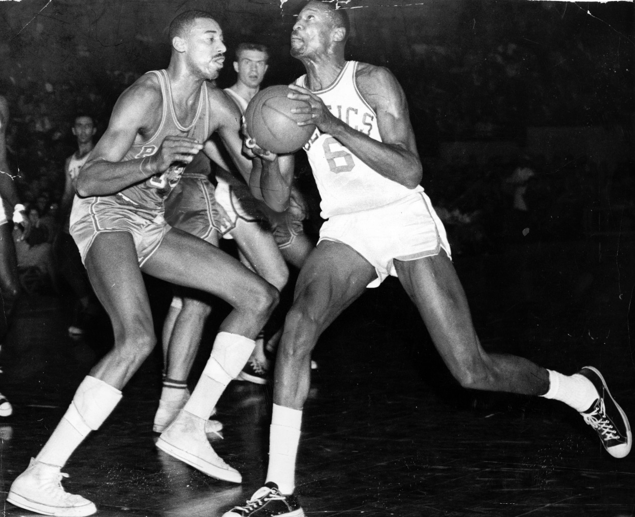 Boston Celtics center Bill Russell drives to the basket around Philadelphia 76ers star Wilt Chamberlain.