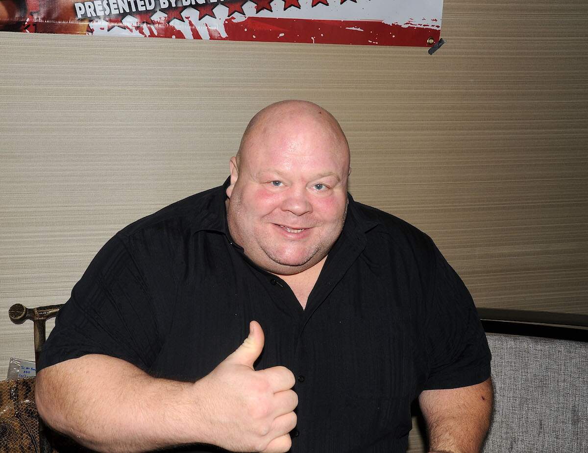 Butterbean, retired boxer, gives a thumbs up to the camera while wearing a black polo shirt