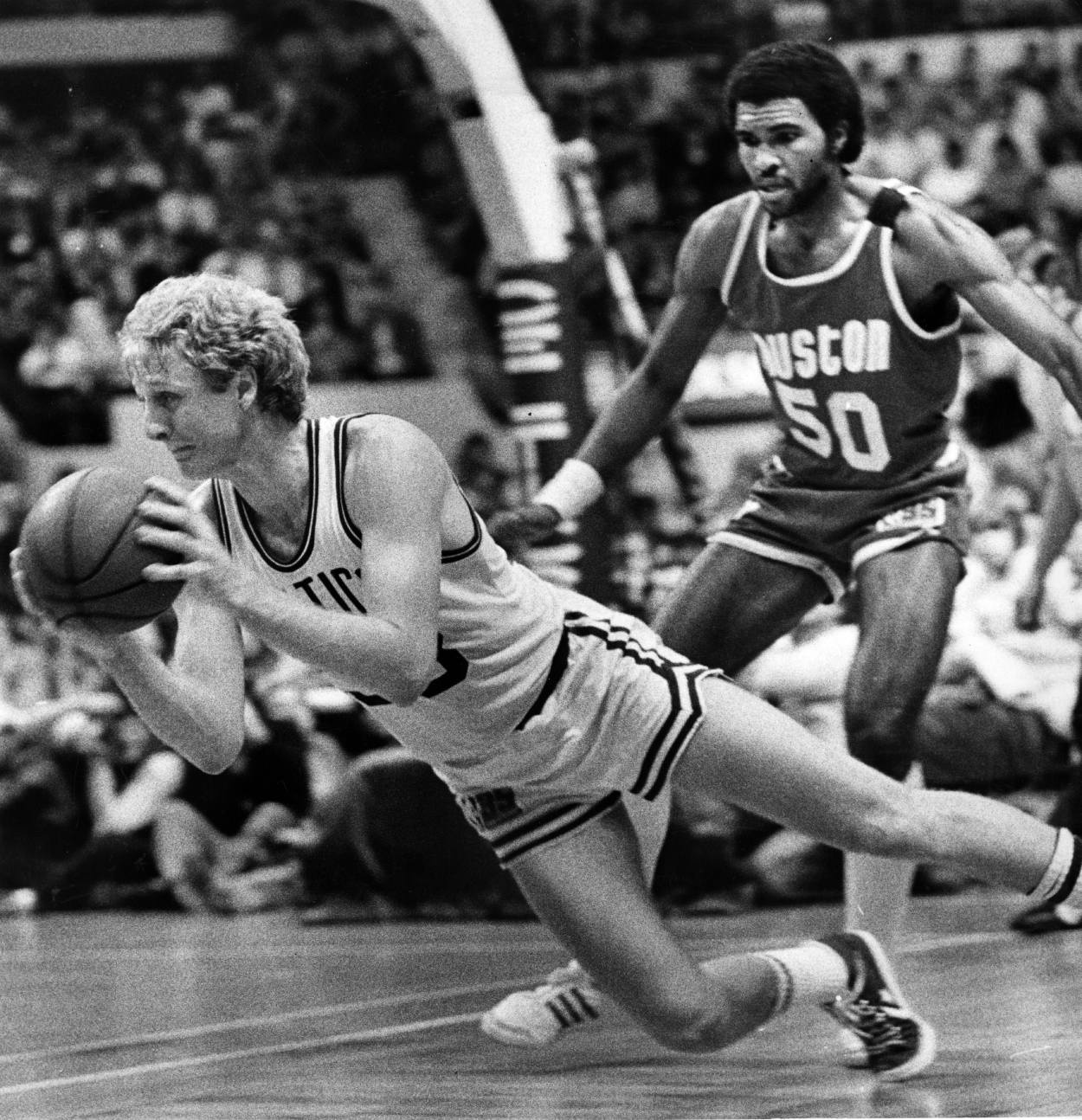 Boston Celtics star Larry Bird, left, can't get a shot off while falling as Houston Rockets player Robert Reid comes in from behind.