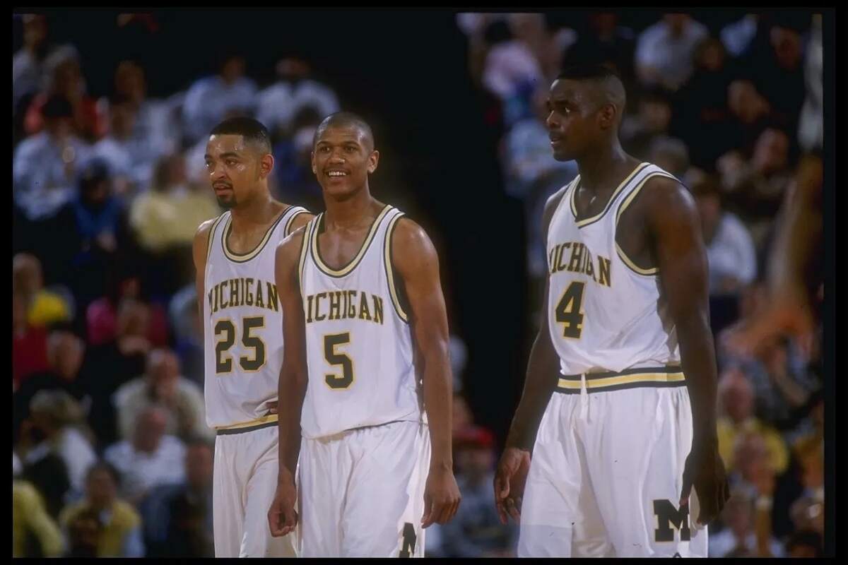 Michigan Wolverines Juwan Howard, Jalen Rose, and Chris Webber walk across the court