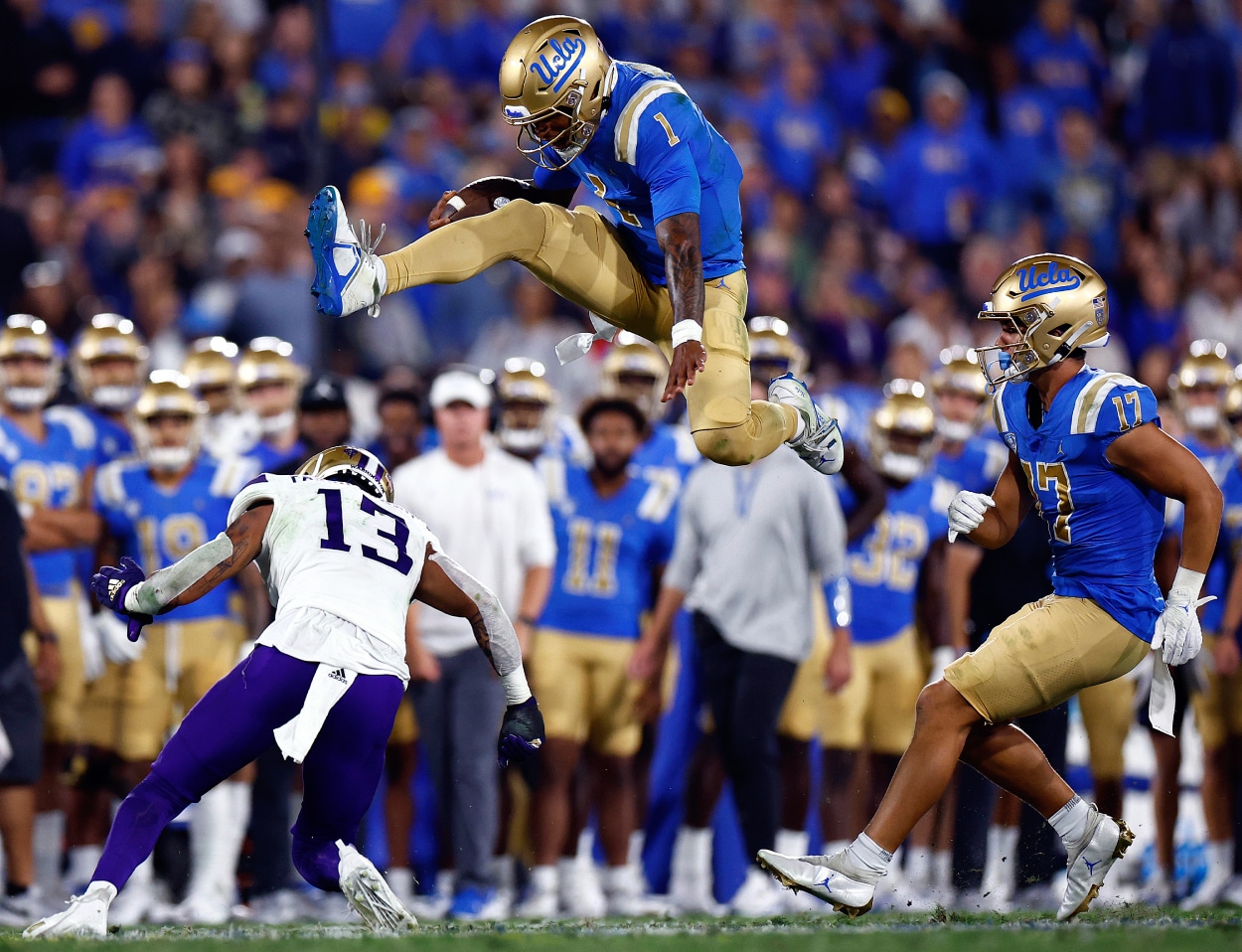 Dorian Thompson-Robinson of the UCLA Bruins jumps over Kamren Fabiculanan of the Washington Huskies.