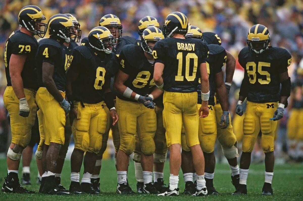 Michigan Wolverines QB Tom Brady instructs his offense line in the huddle during a game against the Purdue Boilermakers in 1999 | Harry How/Getty Images