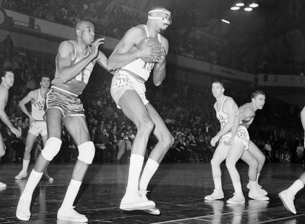 Wilt Chamberlain pulls down a rebound as Warrior Nate Thurmond defends.