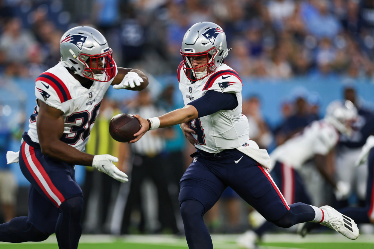 Bailey Zappe of the New England Patriots hands the ball off to Kevin Harris against the Tennessee Titans.