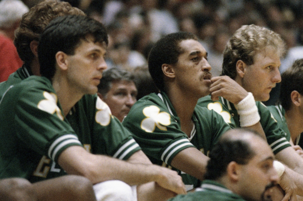 Kevin McHale, Dennis Johnson, and Larry Bird watch from the bench.