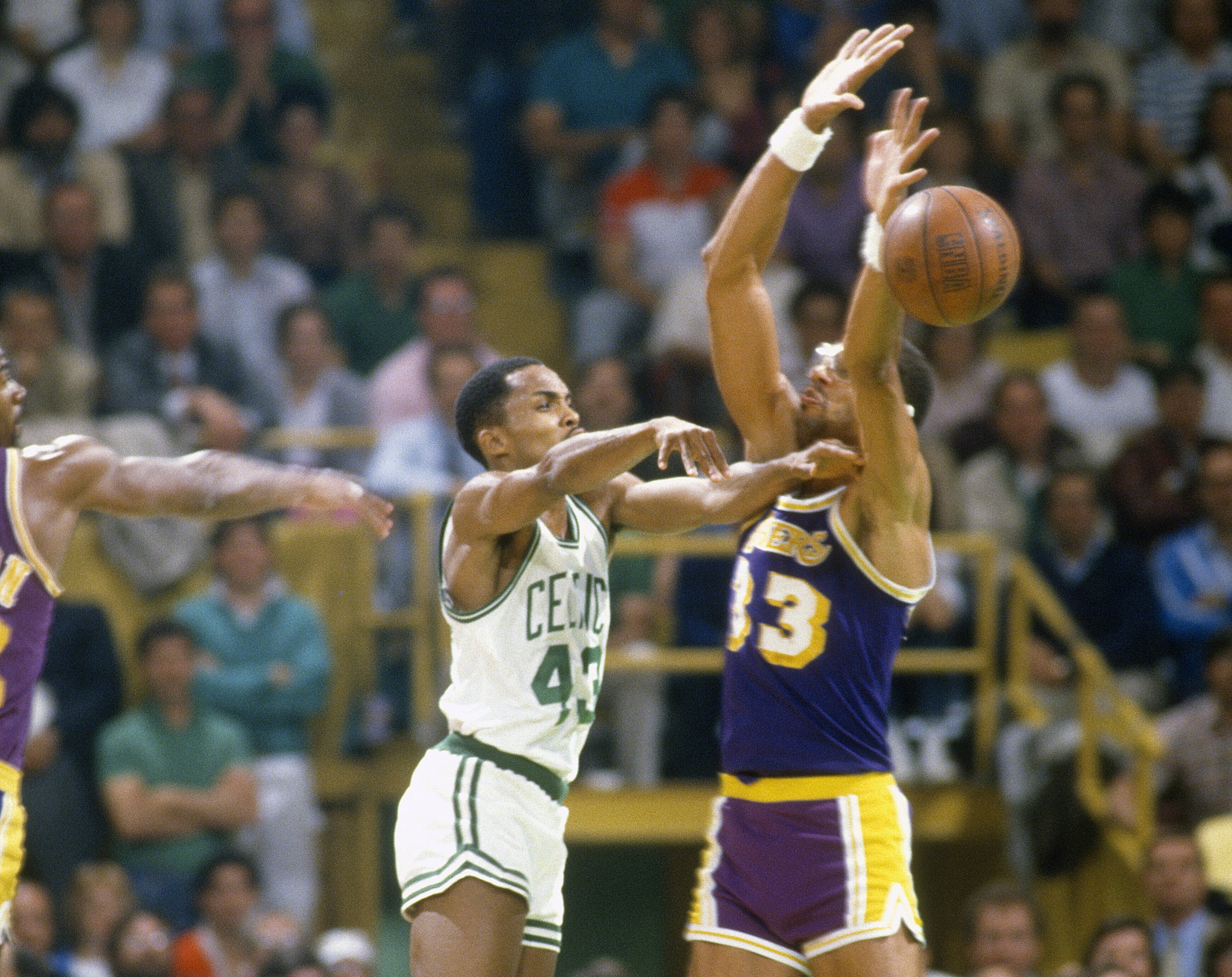 Gerald Henderson of the Boston Celtics passes the ball by Kareem Abdul-Jabbar of the Los Angeles Lakers.
