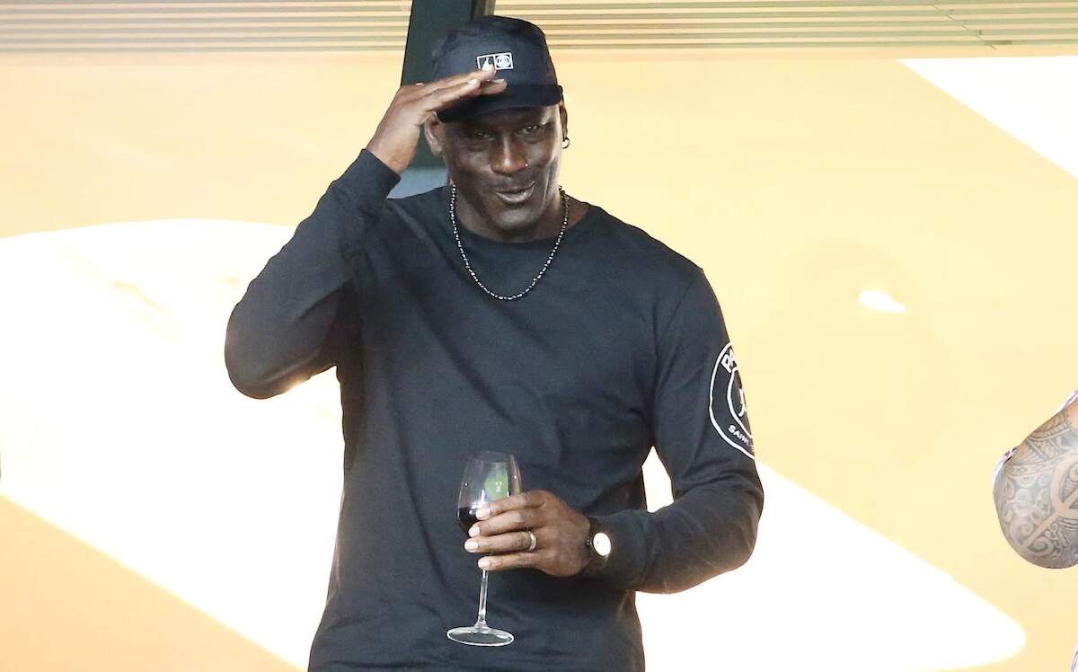 NBA legend Michael Jordan waves to fans at a soccer match while holding a glass of red wine