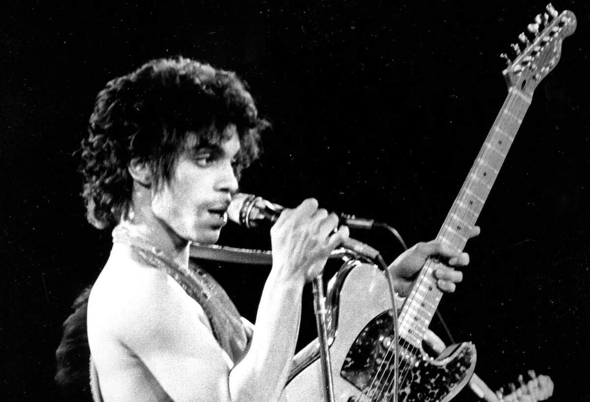 A black and white photo of Prince performing on stage