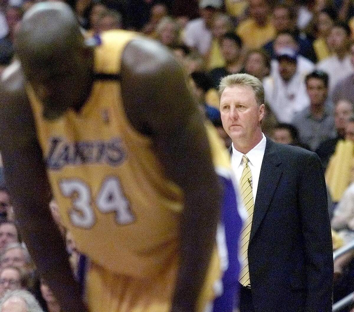 Head coach Larry Bird of the Indiana Pacers looks out at the court and Shaquille O'Neal of the Los Angeles Lakers who's bent over recovering