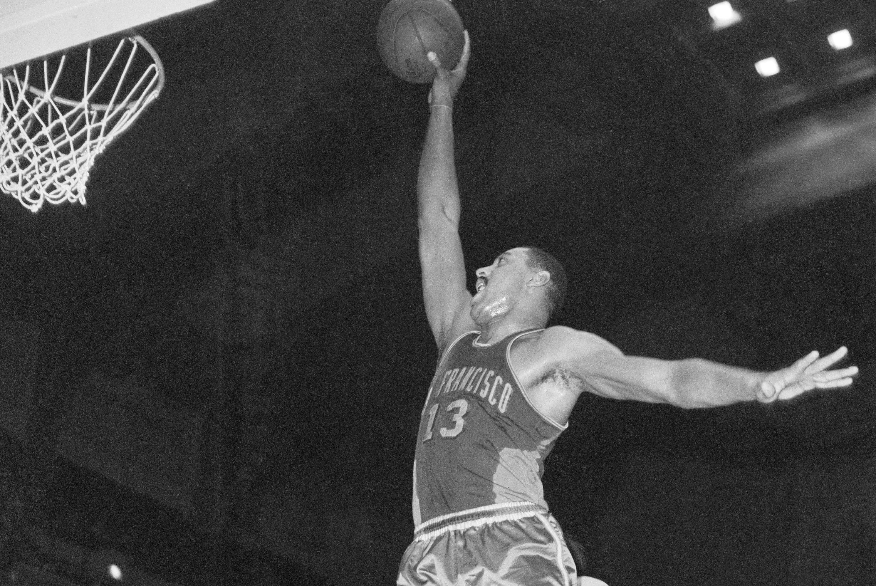San Francisco Warriors star Wilt Chamberlain goes in for a dunk.