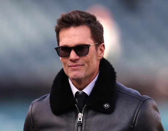 Announcer Tom Brady stands on the sideline.