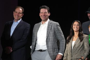 Jim Nantz, Tony Romo, and Tracy Wolfson stand in a line.