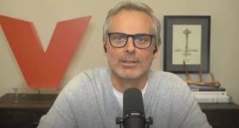 Colin Cowherd sits behind a mic.