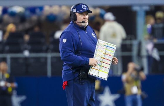 Mike McCarthy holds a sheet on the field.