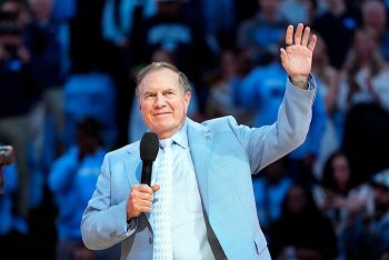 Bill Belichick puts his hands up at a North Carolina basketball game.