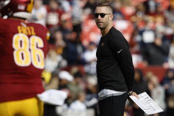 Kliff Kingsbury stands on the field.