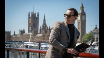 Michael Fassbender holds a book and leans against a rail.